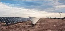  ?? WALDO SWIEGERS Bloomberg ?? PHOTOVOLTA­IC panels stand near electricit­y pylons in the Sishen solar park, operated by Acciona SA, in Kathu, Northern Cape. |