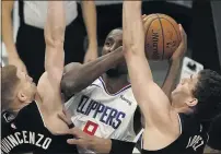  ??  ?? The Clippers’ Serge Ibaka tries to shoot between Milwaukee Bucks’ Donte DiVincenzo and Brook Lopez during the first half.