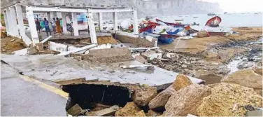  ?? Agence France-presse ?? ↑
Fishermen gather under a faulty structure along a damaged roadside in Gwadar on Thursday.