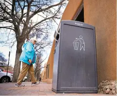  ?? GABRIELA CAMPOS/THE NEW MEXICAN ?? A woman walks by the solar-powered trash compactor at Lincoln and Palace avenues.