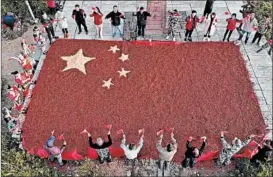  ?? GETTY-AFP ?? Farmers on Wednesday surround a Chinese national flag they made of chili peppers and corn in Lishui, Zhejiang province, to mark the upcoming National Day, which celebrates the founding of the People’s Republic of China on Oct. 1, 1949.