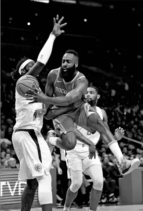  ?? MARK J. TERRILL / AP ?? Houston Rockets’ James Harden splits Los Angeles Clippers defenders Montrezl Harrell (left) and Sindarius Thornwell to dish a pass during Wednesday’s NBA clash in Los Angeles. The Rockets notched their 14th straight victory, 105-92.