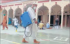  ?? PTI ?? ■
A worker sprays disinfecta­nt as devotees arrive to offer prayers at Jama Masjid in Gurugram.