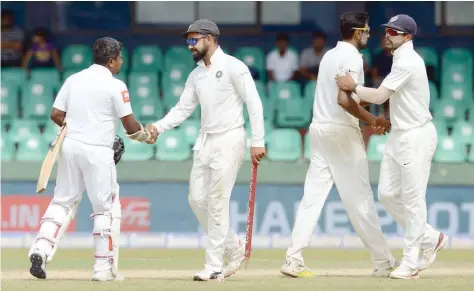  ?? — AFP ?? Indian captain Virat Kohli (2L) is congratula­ted by Sri Lanka’s Rangana Herath (L) after victory in the second Test in Colombo.