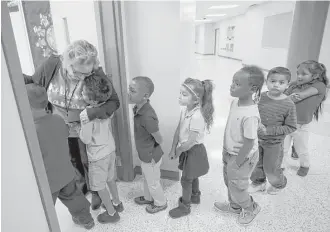  ?? Godofredo A. Vasquez / Houston Chronicle ?? Carolyn Jackson welcomes Doris Irizarry’s kindergart­en students into her art classroom at Robinson Elementary — the first of seven flood-damaged HISD schools to reopen since Harvey.