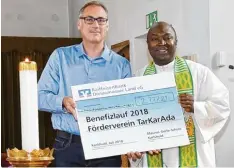  ?? Foto: Roland Geier ?? Rektor Rainer Seefried von der Karlshulde­r Maurus Gerle Schule übergibt den Scheck an Pfarrer Paul Igbo.