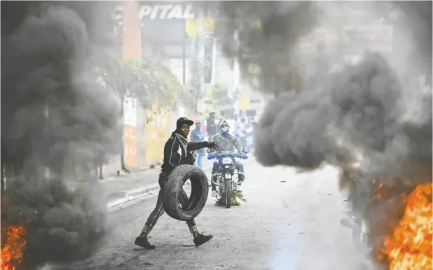  ?? RICHARD PIERRIN / AFP VIA GETTY IMAGES ?? A protester burns tires during a demonstrat­ion calling for the resignatio­n of Prime Minister Ariel Henry, below, in Port-au-prince last month.