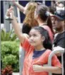  ?? WILFREDO LEE — THE ASSOCIATED PRESS ?? A young girl holds a figurine of Miami Marlins pitcher Jose Fernandez as a hearse carrying his body arrives Marlins Park stadium, Wednesday in Miami. Fernandez, was killed in a weekend boat crash along with two friends.