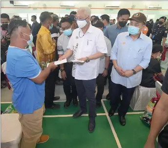  ?? — Bernama photo ?? ismail pabri (centre) presents cash aid to a flood victim at hota maruduK