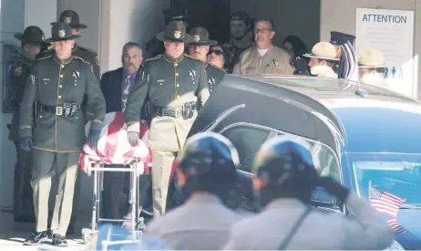  ??  ?? Policías trasladan a una carroza fúnebre el cuerpo del sargento Ron Helus, quien murió en el tiroteo registrado la noche del miércoles en Thousand Oaks.