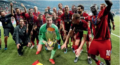  ?? — Reuters ?? WE ARE THE CHAMPIONS: Liverpool goalkeeper Adrian (centre) lifts the trophy as he celebrates winning the Super Cup with teammates.