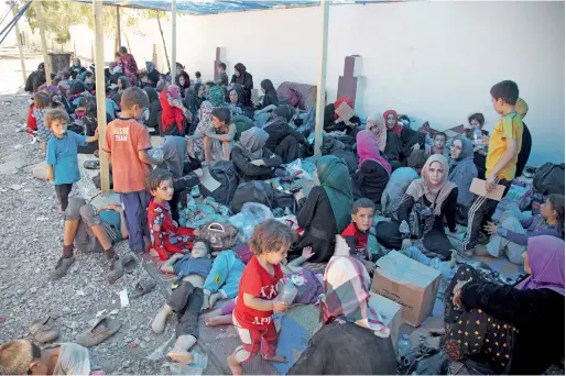  ?? AP ?? Displaced women and children sit on the ground at a collection point for displaced people west of Mosul. —
