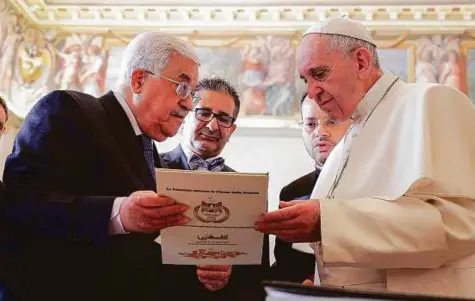  ?? AP ?? Pope Francis is presented with a gift by Palestinia­n President Mahmoud Abbas during a private audience at the Vatican yesterday.