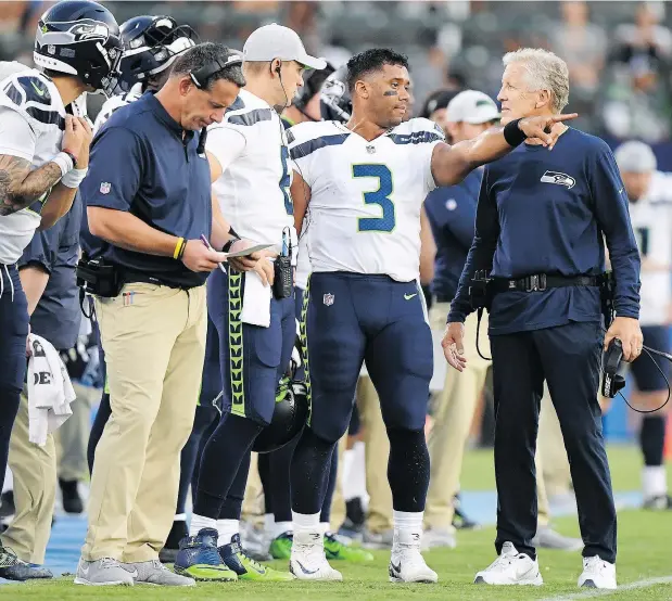  ?? — GETTY IMAGES ?? Quarterbac­k Russell Wilson, second from right, and head coach Pete Carroll, right, will certainly be there for the opening game of the regular season, but the Seattle Seahawks, like every other NFL team, have some difficult roster decisions to make over the next two weeks.