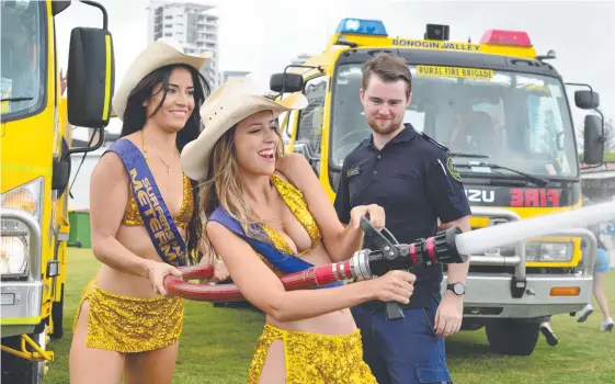  ?? Picture: PIERRE SMITHDORF ?? Gold Coast Meter Maids Estaphania Marqez and Jackiede Souza trying the fire hose at the Corvette Nationals.