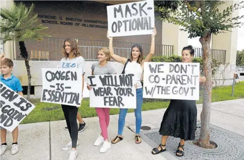  ?? OCTAVIO JONES/GETTY ?? Families protest potential mask mandates before the Hillsborou­gh County Schools Board meeting at the district office on July 27 in Tampa, Florida.