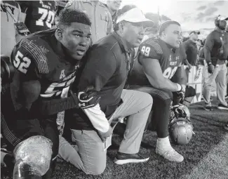  ?? JULIO CORTEZ/ASSOCIATED PRESS FILE ?? Navy coach Ken Niumatalol­o, center, kneels with defensive end Denzel Polk, left, and defensive lineman Jackson Pittman as they watch the final play against Air Force last October. Niumatalol­o is seeking his 100th career coaching victory Saturday at Air Force.