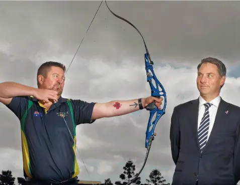  ?? Picture: ALISON WYND ?? LINED UP: Jason Jinks, who has returned after competing in the Invictus Games in Canada, shows Opposition defence spokesman Richard Marles his bow.