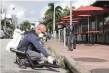  ??  ?? Mosquito control inspector Yasser “Jazz” Compagines sprays a chemical mist into a storm drain Tuesday in Miami Beach, Fla.
