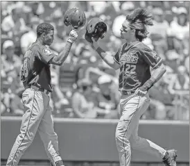  ?? Nati Harnik / The Associated Press ?? Florida State’s Drew Mendoza (right) celebrates with J.C. Flowers after scoring a run in the second inning of Monday’s College World Series game against Cal State Fullerton.