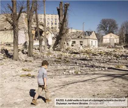  ?? Pictures: AFP ?? RAZED. A child walks in front of a damaged school in the city of Zhytomyr, northern Ukraine.