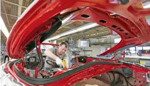  ?? — Reuters ?? A worker assembles a Porsche 911 sports car at a factory in Stuttgart-Zuffenhaus­en.