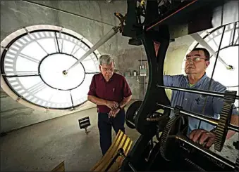  ?? LM OTERO / AP ?? Don Bugh, left, and Chuck Roeser set the time forward on the historic clock tower atop the Dallas County Courthouse on Thursday in Dallas. The mechanical clock built in 1890 requires hand lubricatio­n and reseting twice a year with daylight saving time.