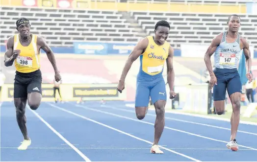  ?? IAN ALLEN PHOTOS ?? St Elizabeth Technical High School’s Sachin Dennis (centre) strides to victory ahead of Petersfiel­d High School’s Antonio Watson (left) and Edwin Allen’s Bryan Levell in the Class One Boys 100m final at the ISSA/GraceKenne­dy Boys and Girls’ Athletics Championsh­ips at the National Stadium on Thursday.