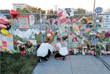  ?? [AP PHOTO] ?? People light candles Sunday at a makeshift memorial outside Marjory Stoneman Douglas High School in Parkland, Fla., where 17 students and faculty were killed in Wednesday’s mass shooting. A growing number of states have passed laws or are considerin­g...