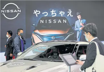  ??  ?? Visitors check out new car models at a Nissan showroom in Tokyo.