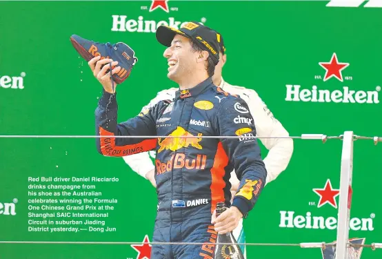  ??  ?? Red Bull driver Daniel Ricciardo drinks champagne from his shoe as the Australian celebrates winning the Formula One Chinese Grand Prix at the Shanghai SAIC Internatio­nal Circuit in suburban Jiading District yesterday. — Dong Jun