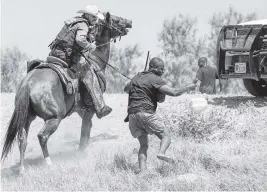  ?? PAUL RATJE AFP via Getty Images ?? A United States Border Patrol agent on horseback uses the reins to try and stop a Haitian migrant from entering an encampment on the banks of the Rio Grande in Del Rio, Texas, on Sunday.