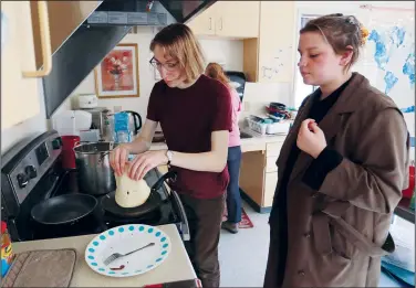  ?? (AP/Cedar Attanasio) ?? Students Sophia Pavlenko (left) of Russia and Masha Novikova of Ukraine prepare blini, the Eastern European-style crepes, to sell to fellow students March 12 in a dorm at the United World College in Montezuma, N.M.