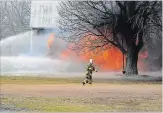  ?? THE WELLAND TRIBUNE FILE PHOTO ?? In this file photo, a Wainfleet firefighte­r walks toward a fire truck as water is streamed toward a house fire behind him.
