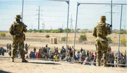  ?? ANDRES LEIGHTON/AP ?? Migrants wait in line adjacent to the border fence under the watch of the Texas National Guard to enter into El Paso, Texas, in May.