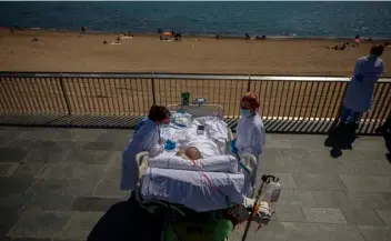  ?? AP Photo/Emilio Morenatti ?? Francisco España, 60, is surrounded by members of his medical team as he looks at the Mediterran­ean sea from a promenade next to the “Hospital del Mar” in Barcelona, Spain, on Friday.