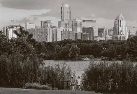  ?? Ralph Barrera / Associated Press file photo ?? Women walk against the Austin skyline. Landing the new Samsung facility would add to a recent string of economic developmen­t wins for Central Texas, including a $1 billion Tesla assembly facility and tech giant Oracle’s corporate headquarte­rs.