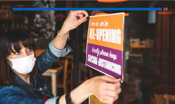  ?? IStock photo ?? A restaurate­ur posts a sign that says she is open for business again—coping with the pandemic.