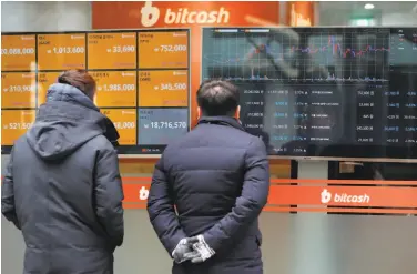  ?? Seong Joon Cho / Bloomberg ?? People look at a monitor of virtual currencies at the Bithumb exchange office in Seoul. A Bail Bloc app produces a cryptocurr­ency called Monero, which is converted into dollars and donated to charity.