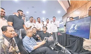  ?? — Gambar Bernama ?? CUBA: Salleh ketika mencuba simulasi komputer kereta lumba sempena ‘Kitamen Equity Crowdfundi­ng Campaign’ di Menara Felda di ibu negara semalam.