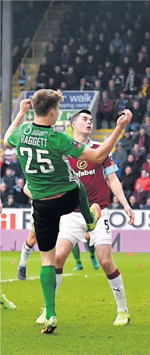  ??  ?? Last-gasp hero: Time seems to stand still at Turf Moor as Sean Raggett’s header floats over the line to send non-league Lincoln into the quarter-finals