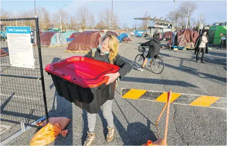  ?? ADRIAN LAM, TIMES COLONIST ?? It’s moving day Monday, as tenters at Royal Athletic Park take up temporary shelter at Save-on-Foods Memorial Centre. Tina Dawson carries a tote to the arena to check herself in. There are 45 beds for the homeless set up at the arena.