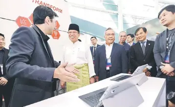  ??  ?? Abang Johari (second left) listens to an exhibitor at SIBEC 2018 while Ting (second right) looks on. — Photo by Chimon Upon