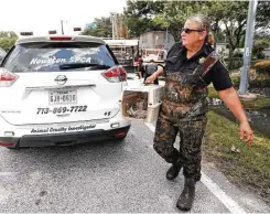  ??  ?? Chris Kendrick carries the rescued cat in a carrier. Rescuers have saved numerous animals since the floodwater­s subsided. “We have everything but alligators,” said community outreach manager Lisa Tynan.