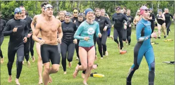  ??  ?? Lifeguard training participan­ts sprint for the lake as part of an endurance challenge.