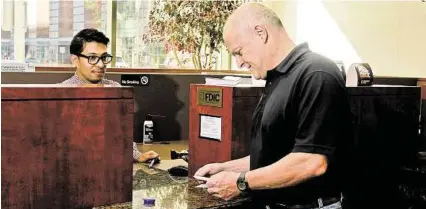  ?? Gary Fountain ?? Teller Adan Camarillo, left, helps customer Steve Clarke at Prosperity Bank’s downtown location.