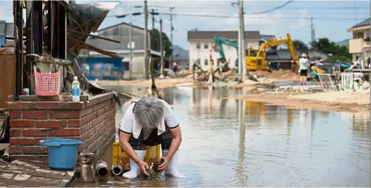  ??  ?? Small comfort:A woman cleaning some of her belongings after her home was damaged in the floods in Mabi.— AFP