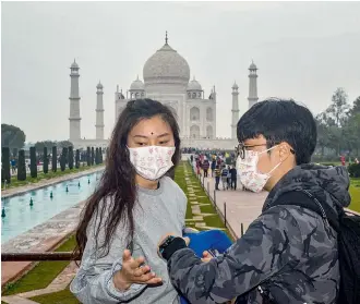  ?? — PTI ?? Tourists wear protective face masks in the wake of the coronaviru­s, at Taj Mahal, in Agra, on Tuesday.