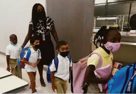  ?? Wilfredo Lee / Associated Press ?? Principal Vernicka Rolle-Murray leads masked students to classrooms Tuesday at Washington Elementary School in Riviera Beach, Fla.