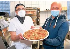  ?? FOTO: JÜRGEN MOLL ?? Pizza-Bäcker Tony und Kolpinghau­s-Pächter Walter Milone mit der ersten Pizza Siciliana. Ab Freitag wird das Angebot nochmals erweitert.